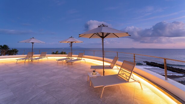 A terrace with sun loungers and umbrellas overlooking the sea. - Atagawa Ocean Resort (Higashiizu)