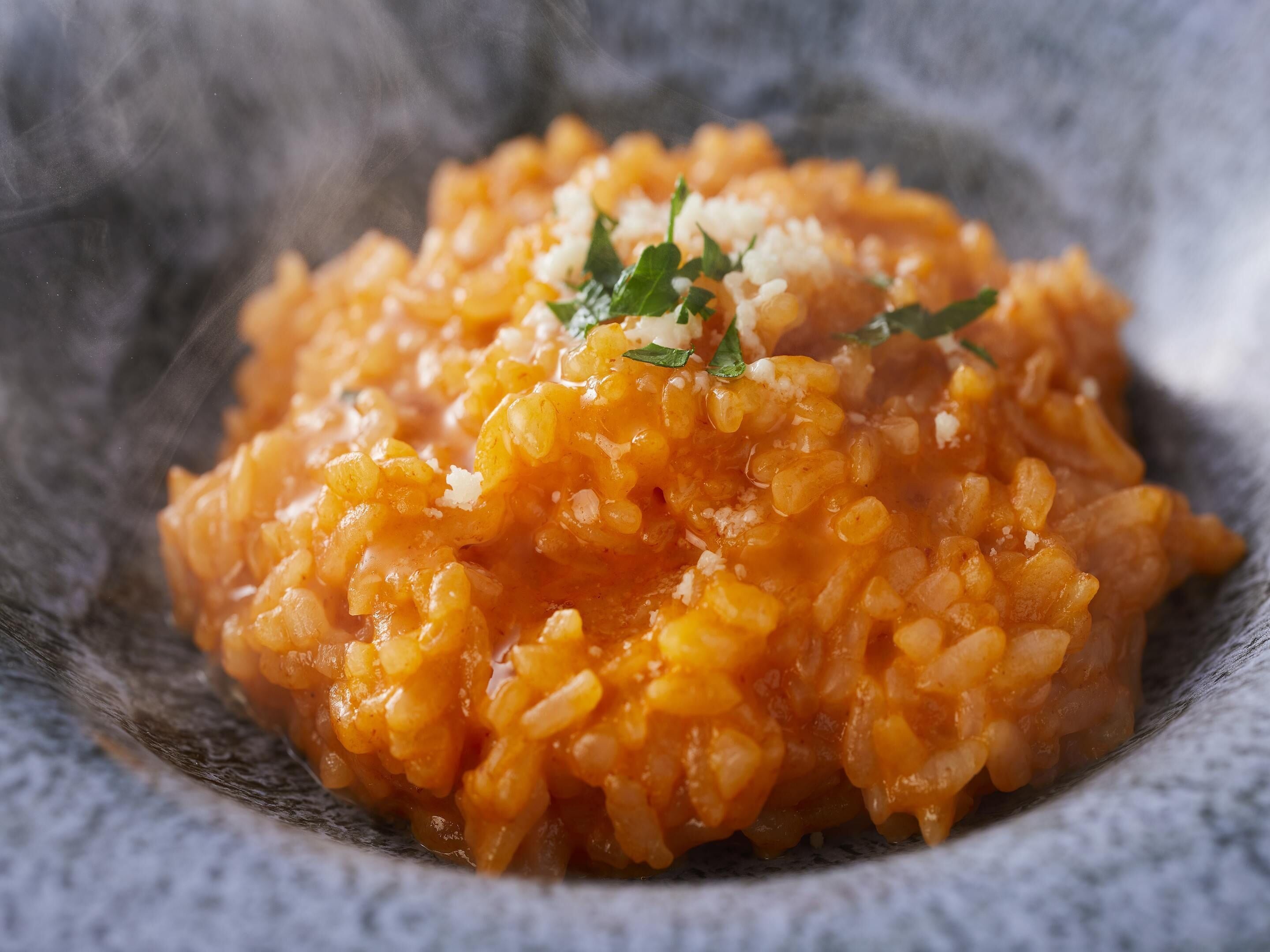 A close-up of a dish with a creamy orange sauce, garnished with herbs and grated cheese.