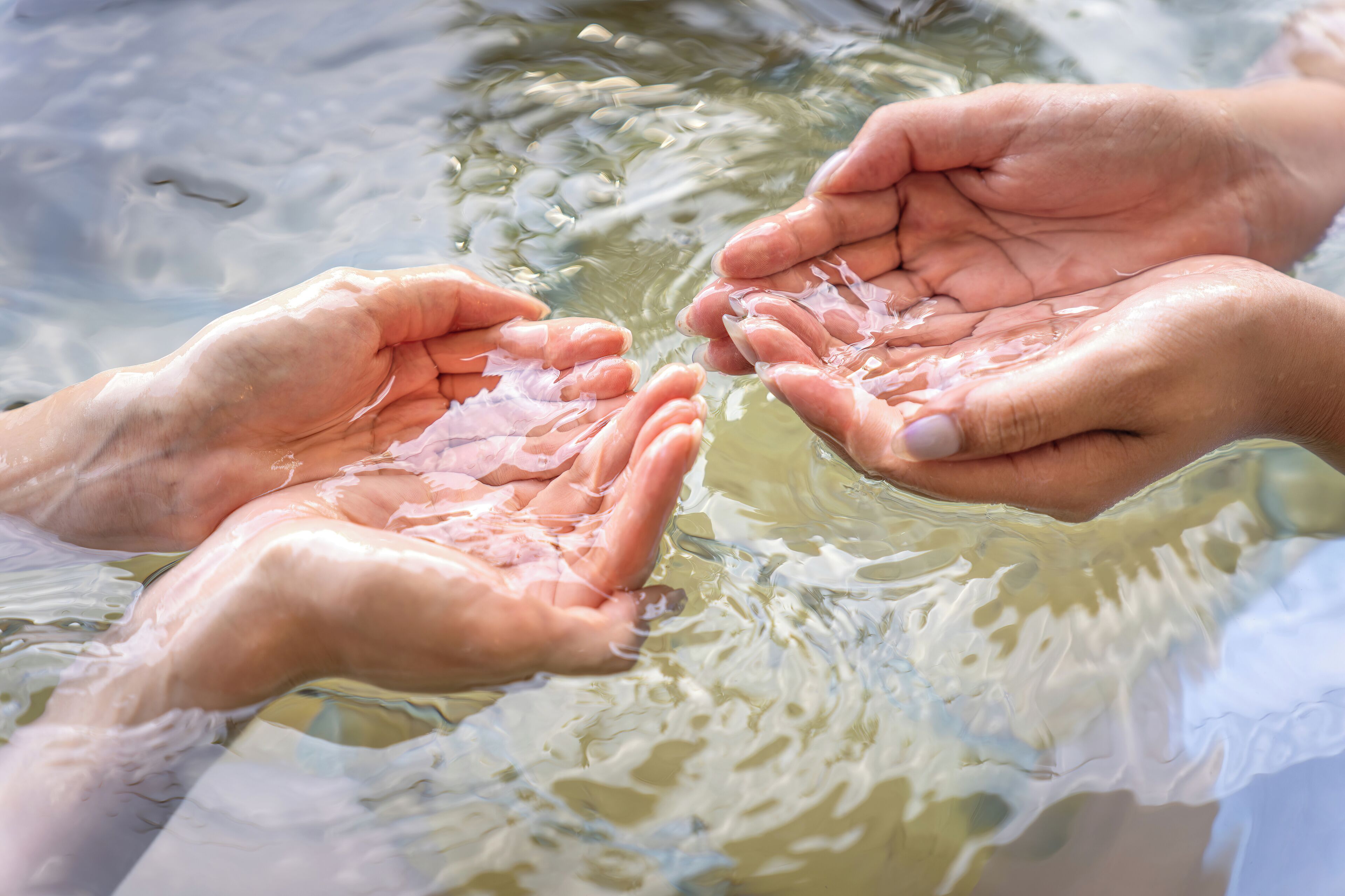Mani unite sopra una superficie d'acqua.