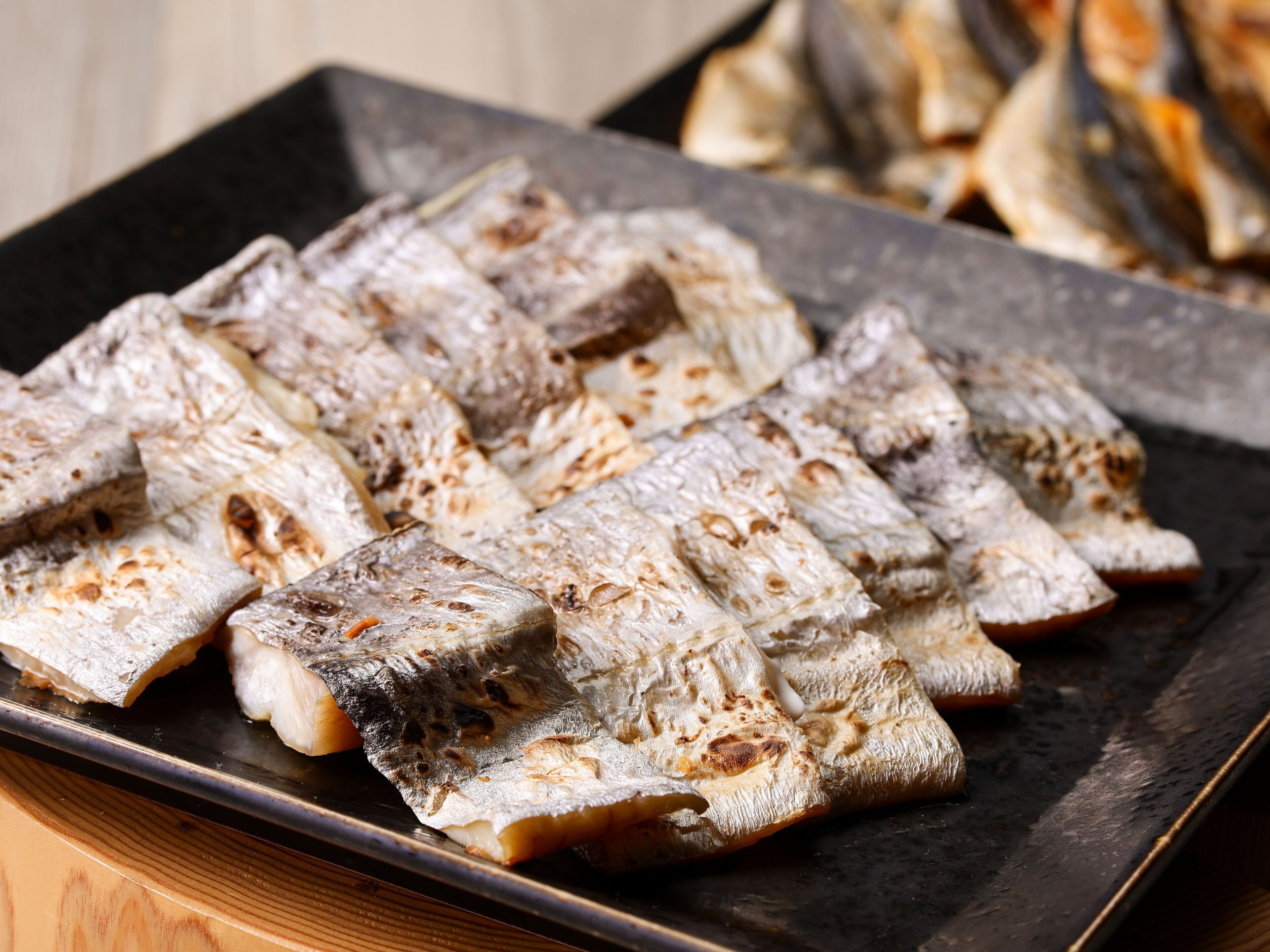 Grilled fish arranged on a dark plate.