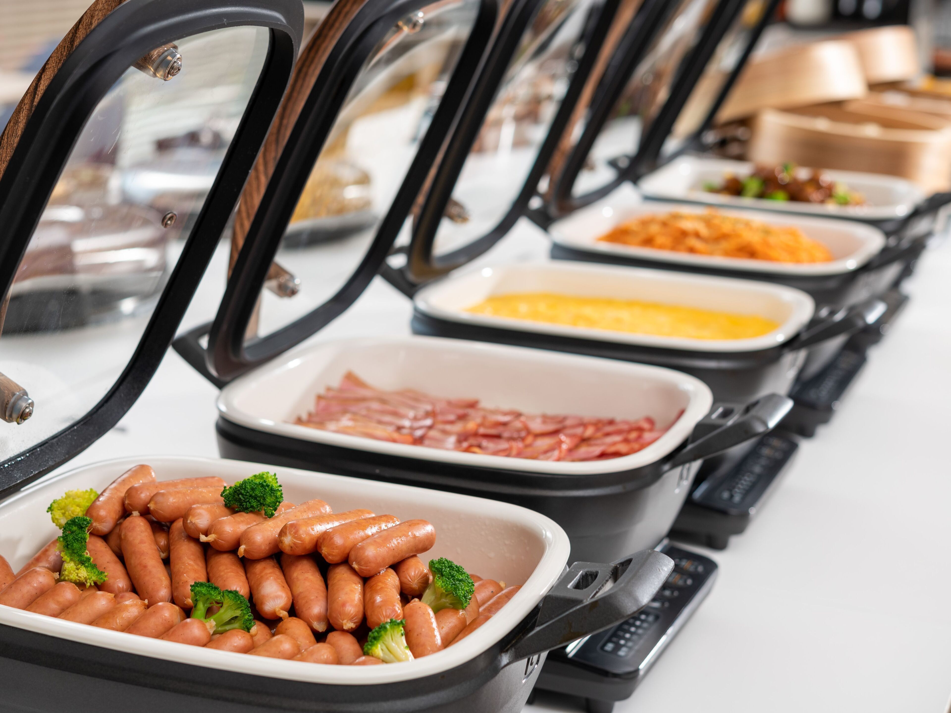 Un buffet proposant une variété de plats, notamment des saucisses, du jambon et d’autres mets.