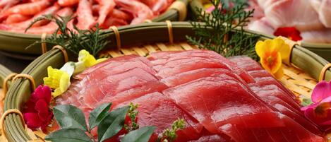 A variety of fresh seafood including shrimp and sashimi on woven baskets.
