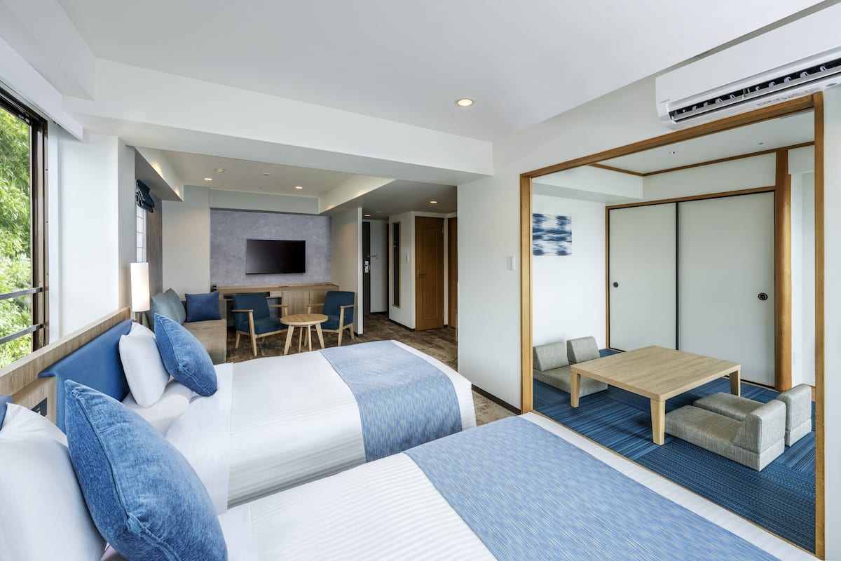 Una habitación de hotel moderna con dos camas, un comedor y un televisor.