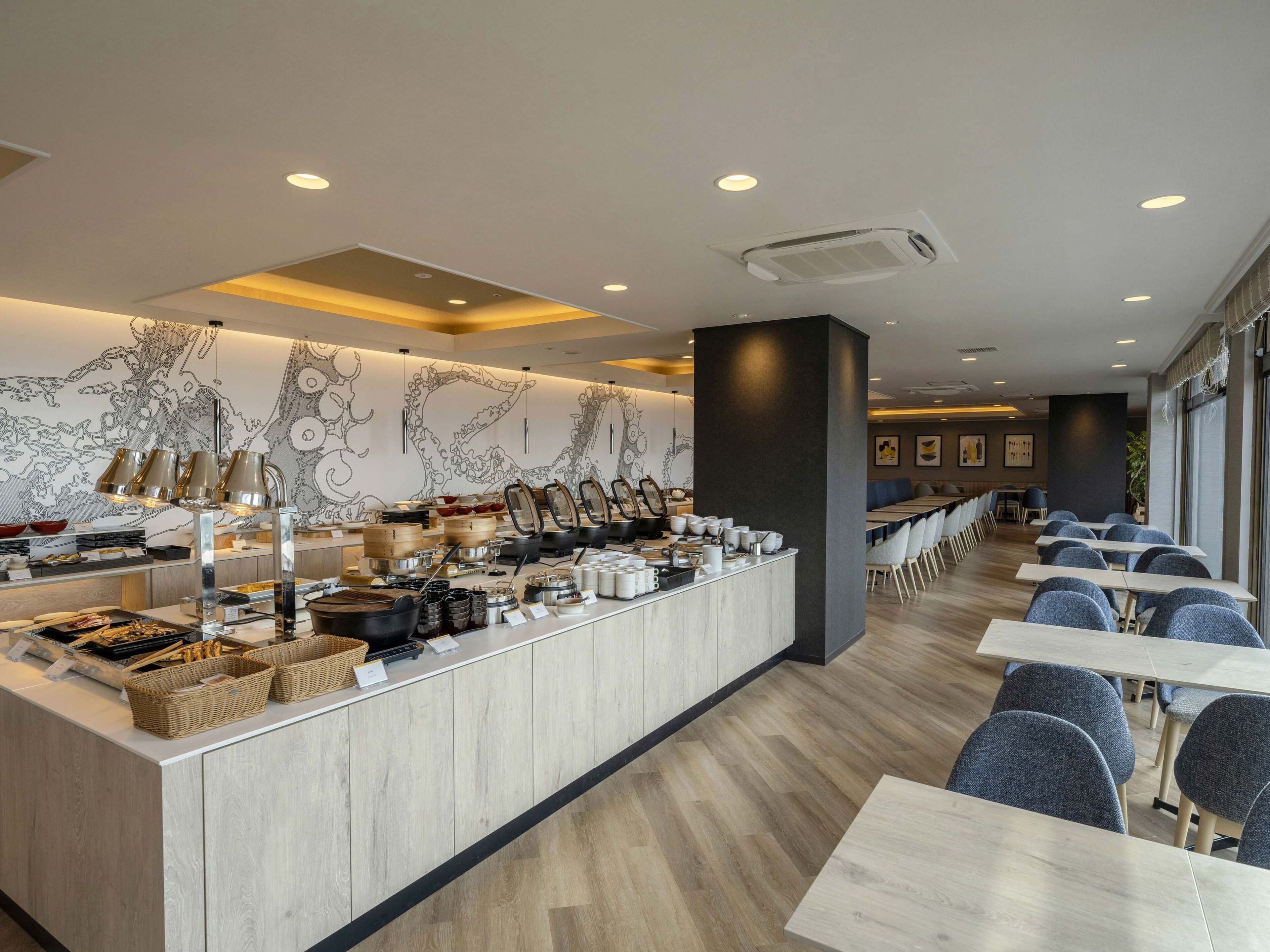 A modern restaurant with a long counter, various dishes, and seating area.