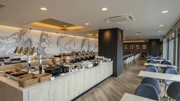 A modern restaurant with a long counter, various dishes, and seating area.