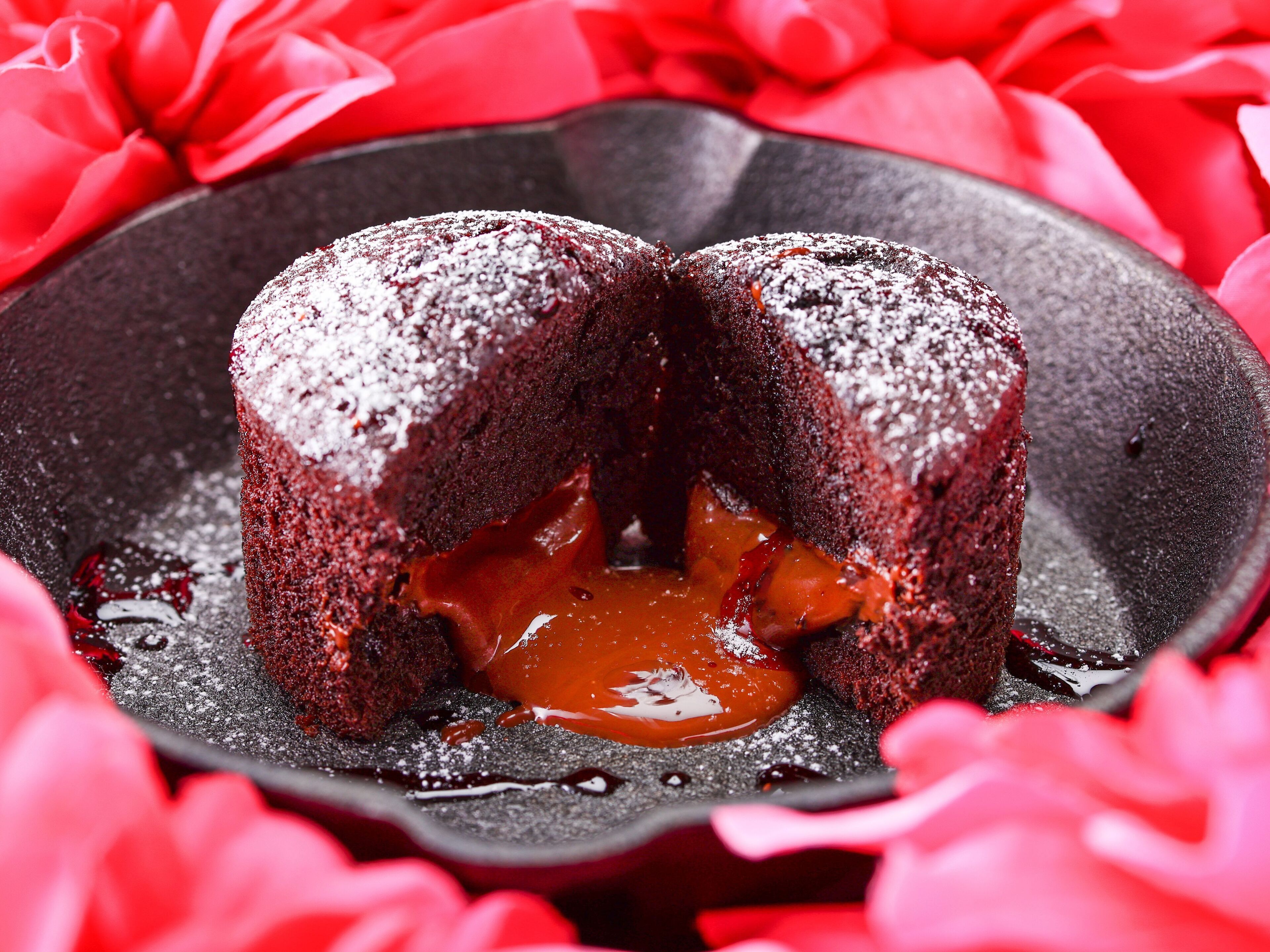 A dessert with a molten center, surrounded by red petals.