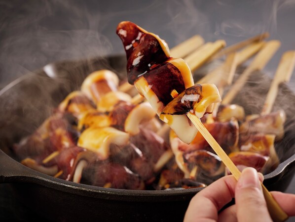 Primer plano de carne ensartada cocinándose sobre llamas abiertas.
