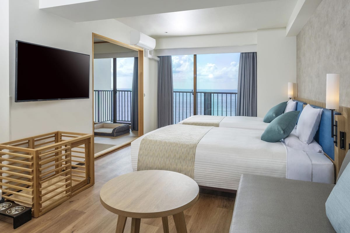 Una habitación de hotel con cama, televisión, balcón y zona de comedor.
