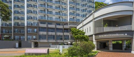 A multi-story hotel building with a modern design, featuring balconies and air conditioning units.