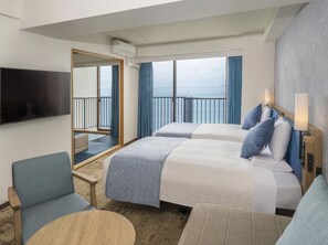 A hotel room with two beds, a TV, a balcony with a view of the sea, and a seating area with a table. - Atagawa Ocean Resort (Higashiizu)