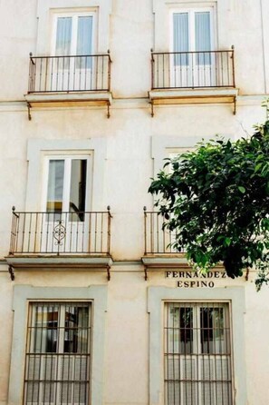 A building with multiple windows, balconies, and a sign reading 'FERNANDEZ ESPINO'.