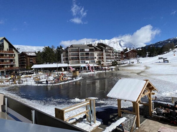 A hotel with multiple floors, outdoor seating areas, and a view of a snowy mountain.