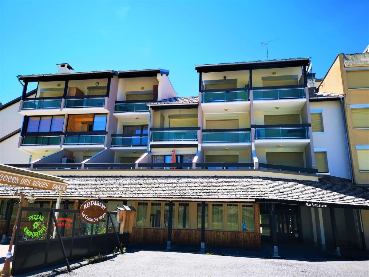 A multi-story building with balconies, a restaurant sign, and a sign for a pizza place.