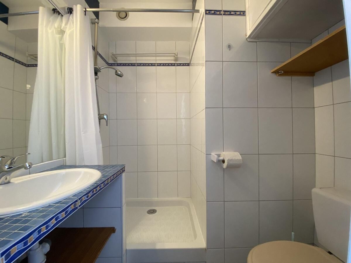 A bathroom with a white sink, a shower, and a toilet.