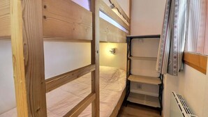 A compact room with a bunk bed, a small shelf unit, and a radiator. - 10m from ski slopes, 5th floor, balcony, ski locker, 20m², Méribel-Mottaret (Méribel - Les Allues)