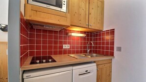 A compact kitchen with a microwave, stove, sink, and dishwasher. - 10m from ski slopes, 5th floor, balcony, ski locker, 20m², Méribel-Mottaret (Méribel - Les Allues)