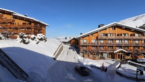 A wooden hotel with multiple balconies and a ski slope in the background. - 10m from ski slopes, 1st floor, balcony, ski locker, 20m², Méribel-Mottaret (Méribel - Les Allues)