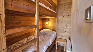 A wooden cabin room with bunk beds, a small bedside table, and a wall-mounted light fixture. - 10m from ski slopes, 1st floor, balcony, ski locker, 20m², Méribel-Mottaret (Méribel - Les Allues)