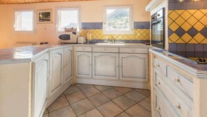 A kitchen with wooden cabinets, a tiled backsplash, and a window with a mountain view.