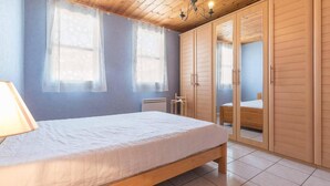 A bedroom with a wooden bed, a nightstand, a wardrobe, and a window with curtains.