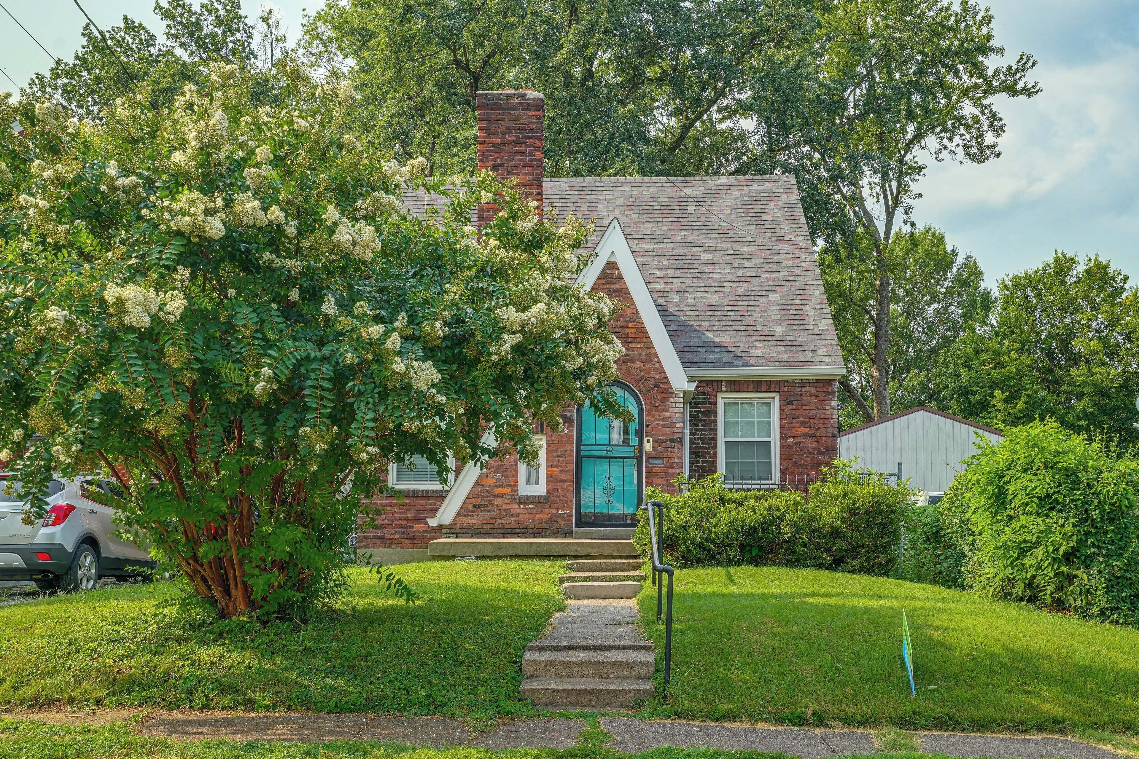 A two-story house with a brick chimney, a blue door, and a small front porch.