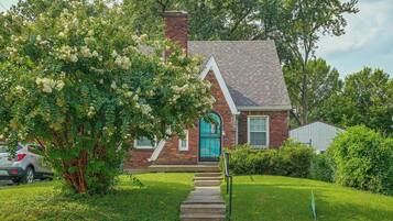 A two-story house with a brick chimney, a blue door, and a small front porch.