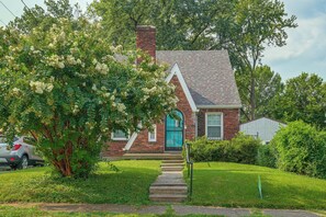 A two-story house with a brick chimney, a blue door, and a small front porch.