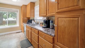 A kitchen with wooden cabinets, a stainless steel sink, and a coffee maker. - Near Churchill Downs: Pet Friendly, Fenced Yard! (Louisville)