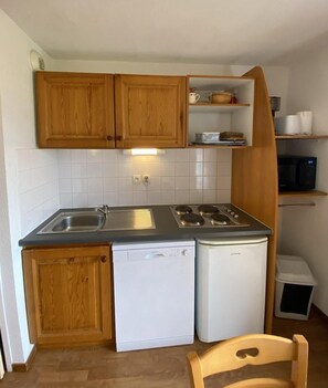 Una cucina compatta con mobili in legno, lavastoviglie integrata e forno a microonde.
