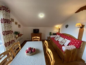 Una stanza accogliente con tavolo da pranzo, sedie, divano, televisore e lampada.
