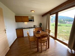 A kitchen with wooden cabinets, a microwave, and a dining table with chairs.