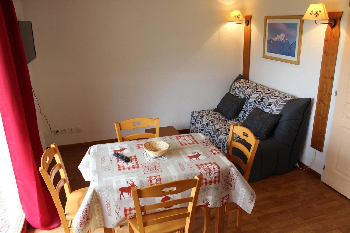 A cozy room with a dining table, chairs, a sofa, and a lamp.