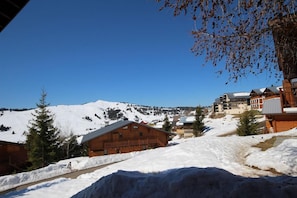 Un pueblo nevado en la montaña con edificios de madera y un cielo azul despejado.