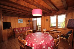 A cozy wooden cabin with a round table covered in a heart-patterned tablecloth, a sofa, a TV, and a desk with a lamp. - Ground floor, view ski slopes, balcony, tv, 32m², Les Saisies (Hauteluce)