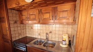 Een keuken met houten kastjes, een dubbele spoelbak, een fornuis en een koffiezetapparaat.