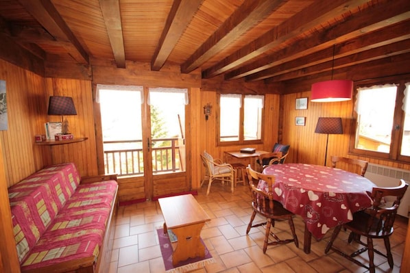 A cozy cabin interior with a wooden interior, a dining table with chairs, a sofa, and a small table.