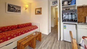 A compact living space with a sofa, a small dining table, a bench, a kitchenette, and a door leading to another room. - 2nd floor, balcony, tv, 24m², Les Menuires (Les Menuires)