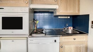 Eine kompakte Küche mit Herd, Backofen, Geschirrspüler und Spüle.