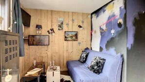 Ein Zimmer mit einem blauen Sofa, Holzwänden, einem aufgehängten Gemälde und einem Cowhide-Teppich.