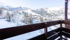 A view from a balcony with a wooden railing, overlooking a snow-covered landscape with mountains and a town below. - 5m from ski slopes, 9th floor, view panoramic, ski locker, 58m², Valmorel (Valmorel)