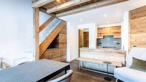 A modern interior with a wooden staircase, a kitchen with wooden cabinets, a dining area with a table and chairs, and a sofa. - 5m from ski slopes, 9th floor, view panoramic, ski locker, 58m², Valmorel (Valmorel)