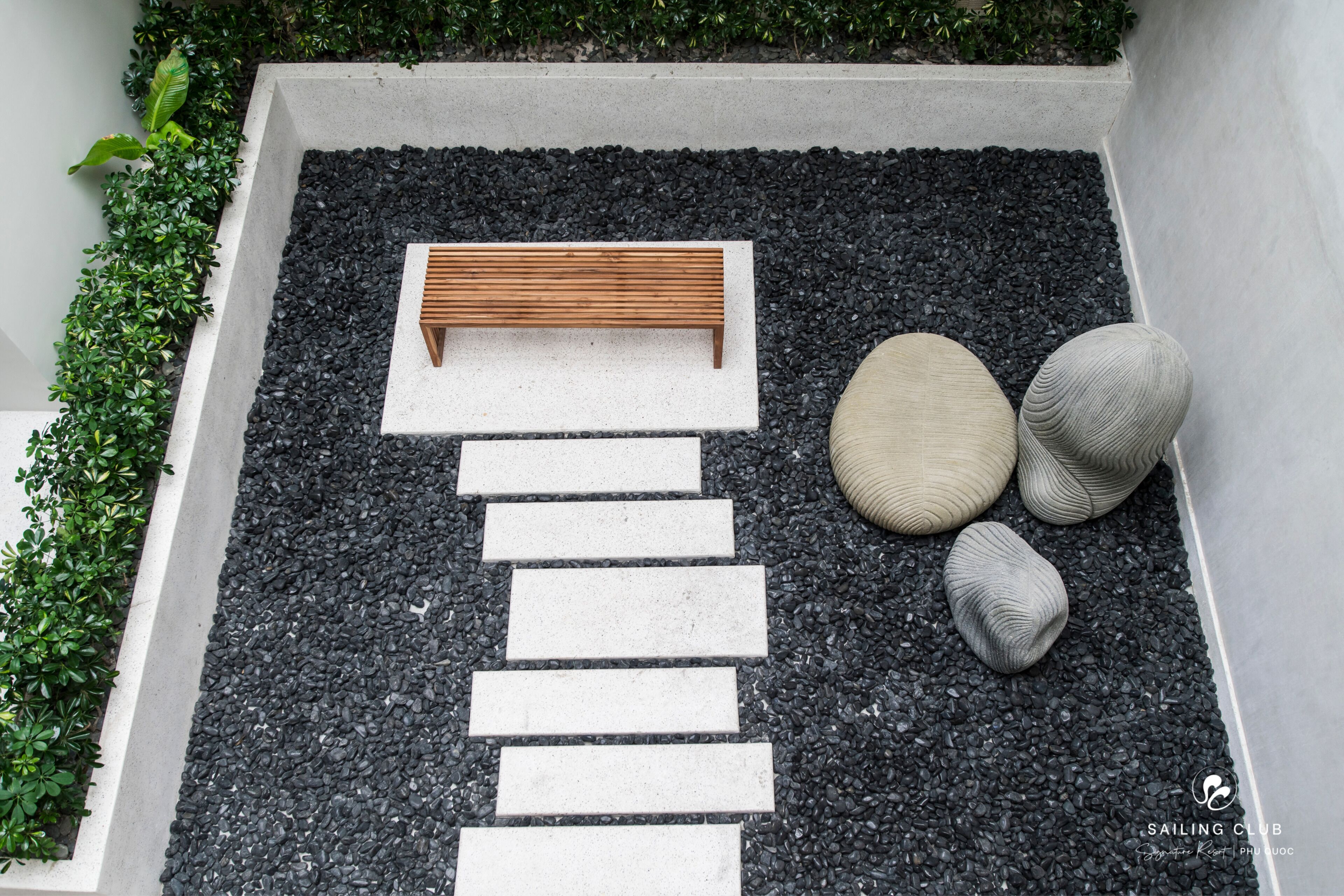 A modern outdoor seating area with a wooden bench, stone steps, and decorative stones.