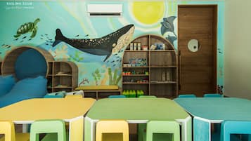 Een kinderspeelkamer met kleurrijk meubilair, een muurschildering van zeedieren en een houten boekenkast.