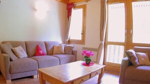 A cozy living room with a sofa, a coffee table, and a window with curtains. - 90m from shops, 5th floor, view mountain, balcony, tv, ski locker, 75m², Valmorel (Valmorel)