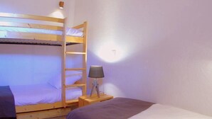 A bunk bed room with a wooden ladder, a bedside table with a lamp, and a single bed with a blanket. - 90m from shops, 5th floor, view mountain, balcony, tv, ski locker, 75m², Valmorel (Valmorel)