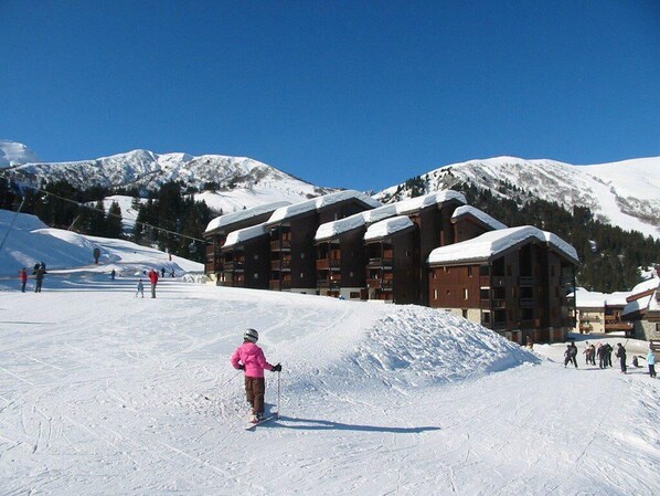 A ski resort with a large lodge, snow-covered mountains, and skiers on the slopes.