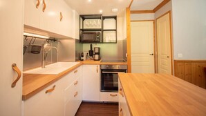 A compact kitchen with white cabinets, wooden countertops, a built-in microwave, and a coffee maker.