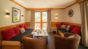 A cozy room with a sofa, two chairs, a small table, and a window with curtains.