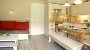 A modern kitchen with white cabinets, a wooden dining table, and a bench. - 250m from shops, 1st floor, balcony, ski locker, 55m², Valmorel (Valmorel)