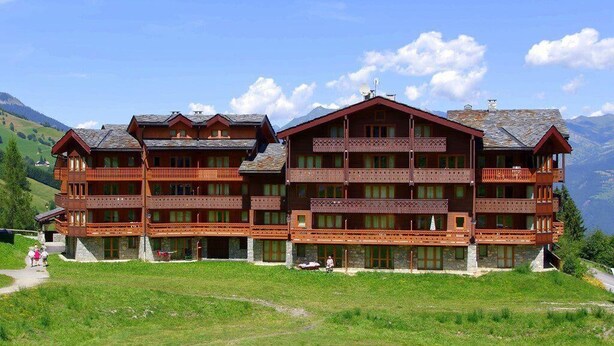 A multi-story wooden building with balconies, set against a mountainous backdrop. - 250m from shops, 1st floor, balcony, ski locker, 55m², Valmorel (Valmorel)